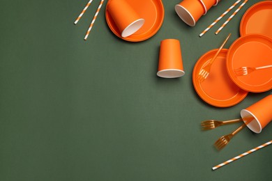 Photo of Disposable tableware on dark green background, space for text