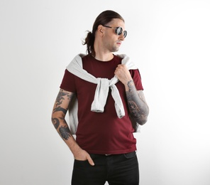 Photo of Young man with stylish tattoos on white background