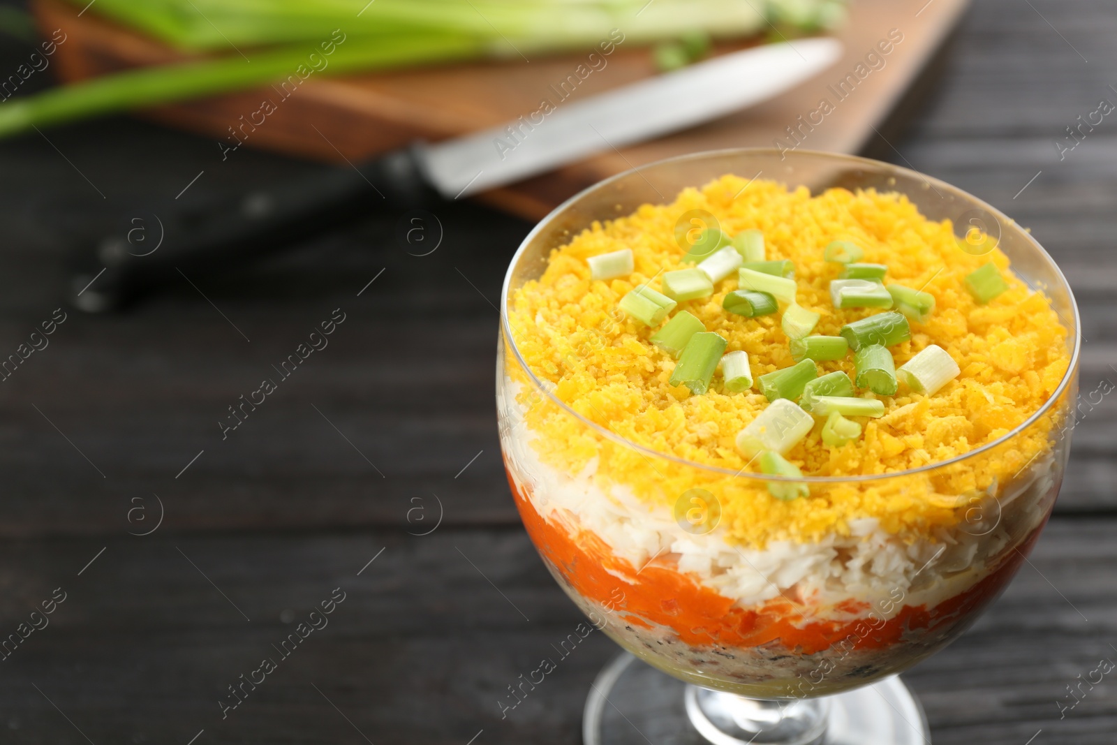 Photo of Traditional russian salad Mimosa served on dark wooden table. Space for text