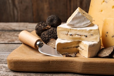 Photo of Different types of cheese, knife and fresh truffles on wooden table