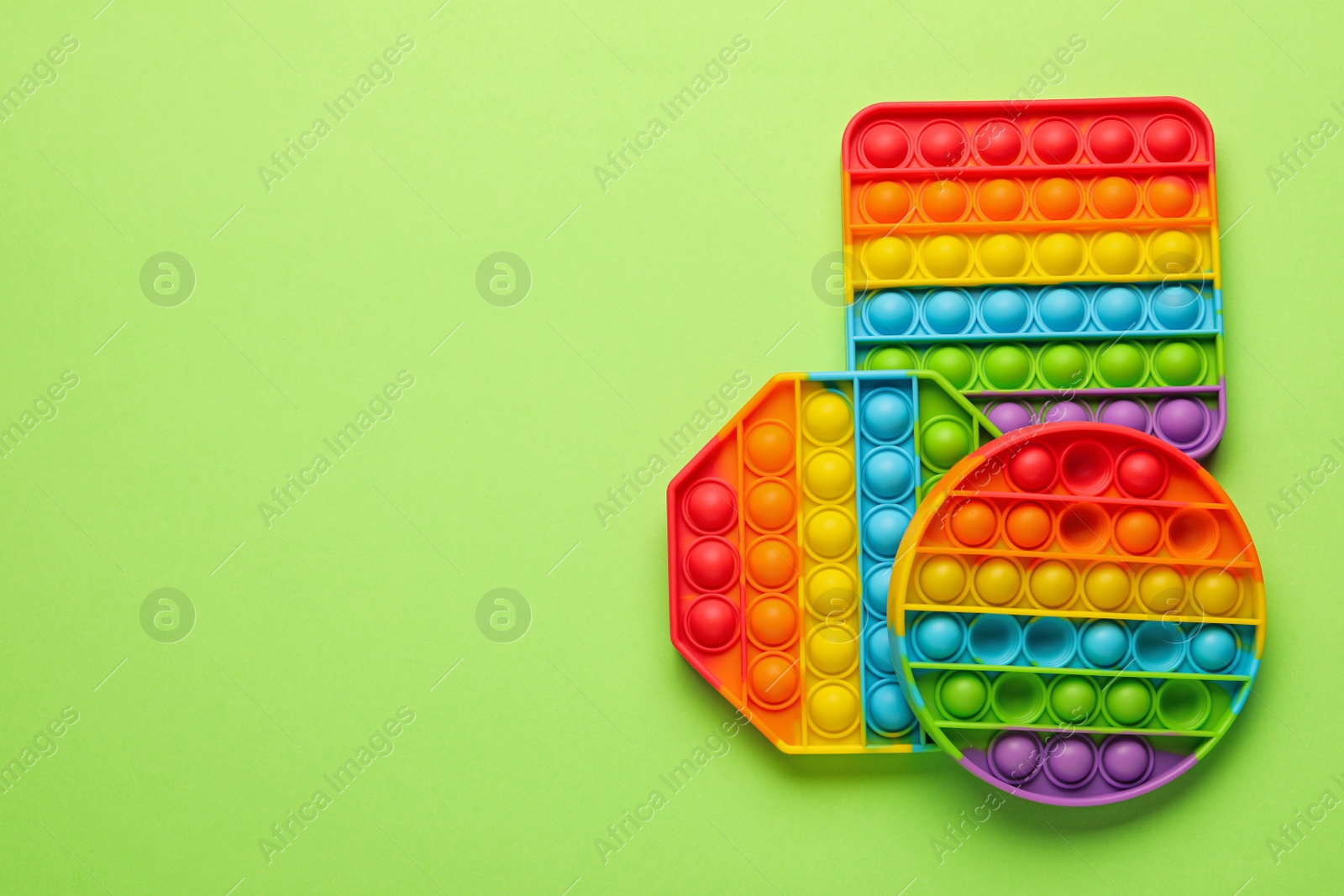 Photo of Rainbow pop it fidget toys on light green background, flat lay. Space for text