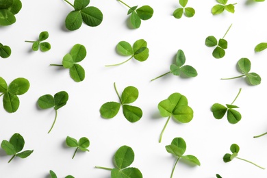 Flat lay composition with green clover leaves on white background, top view