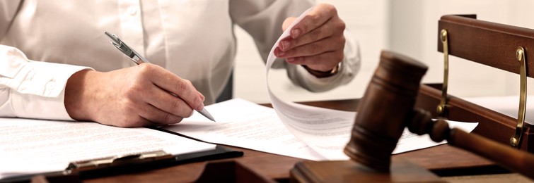 Image of Lawyer working with document at wooden table in office, closeup. Banner design