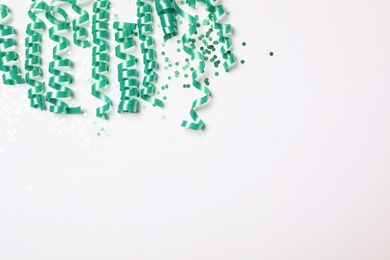 Photo of Turquoise serpentine streamers and confetti on white background, top view