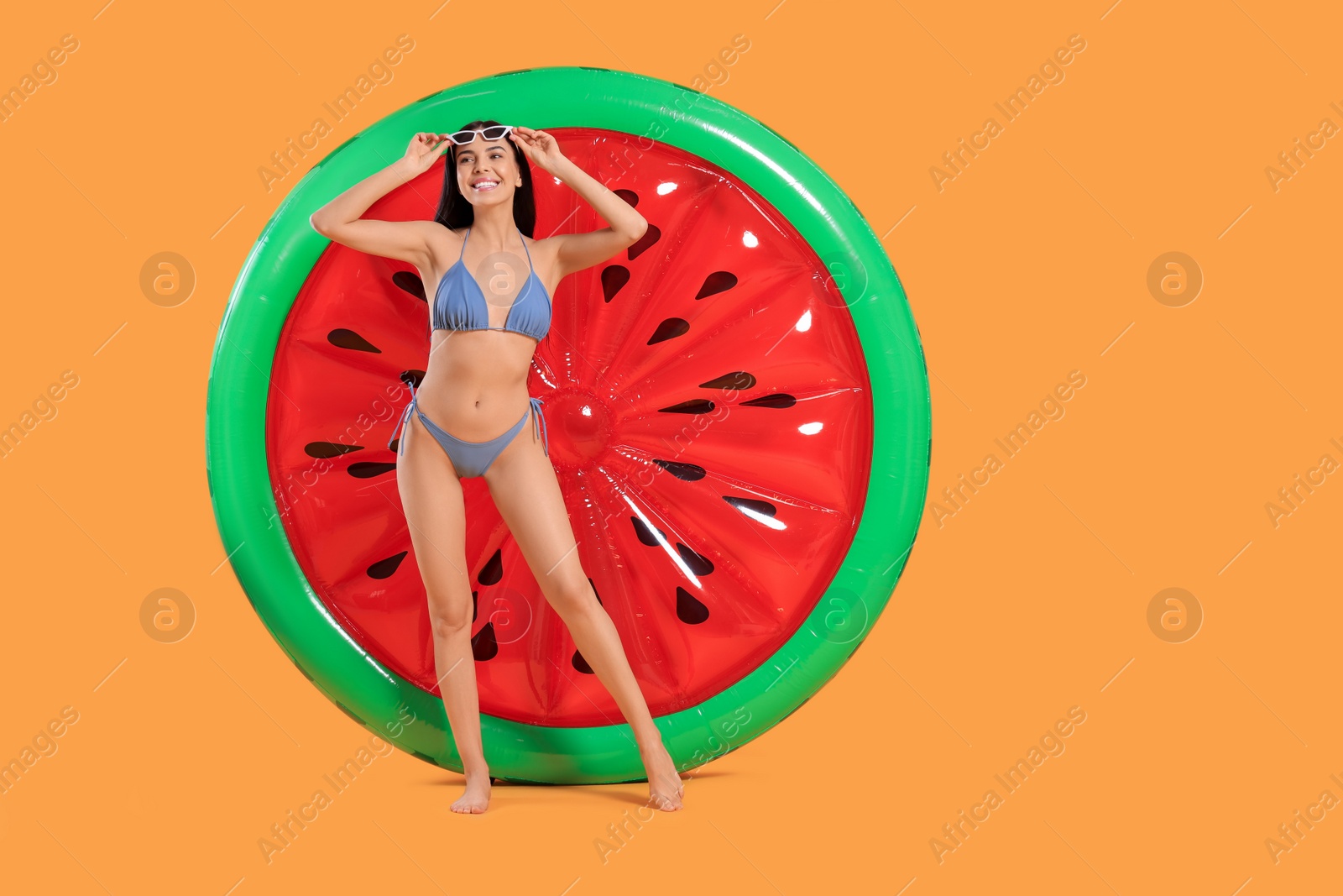 Photo of Happy young woman with beautiful suntan, sunglasses and inflatable mattress against orange background