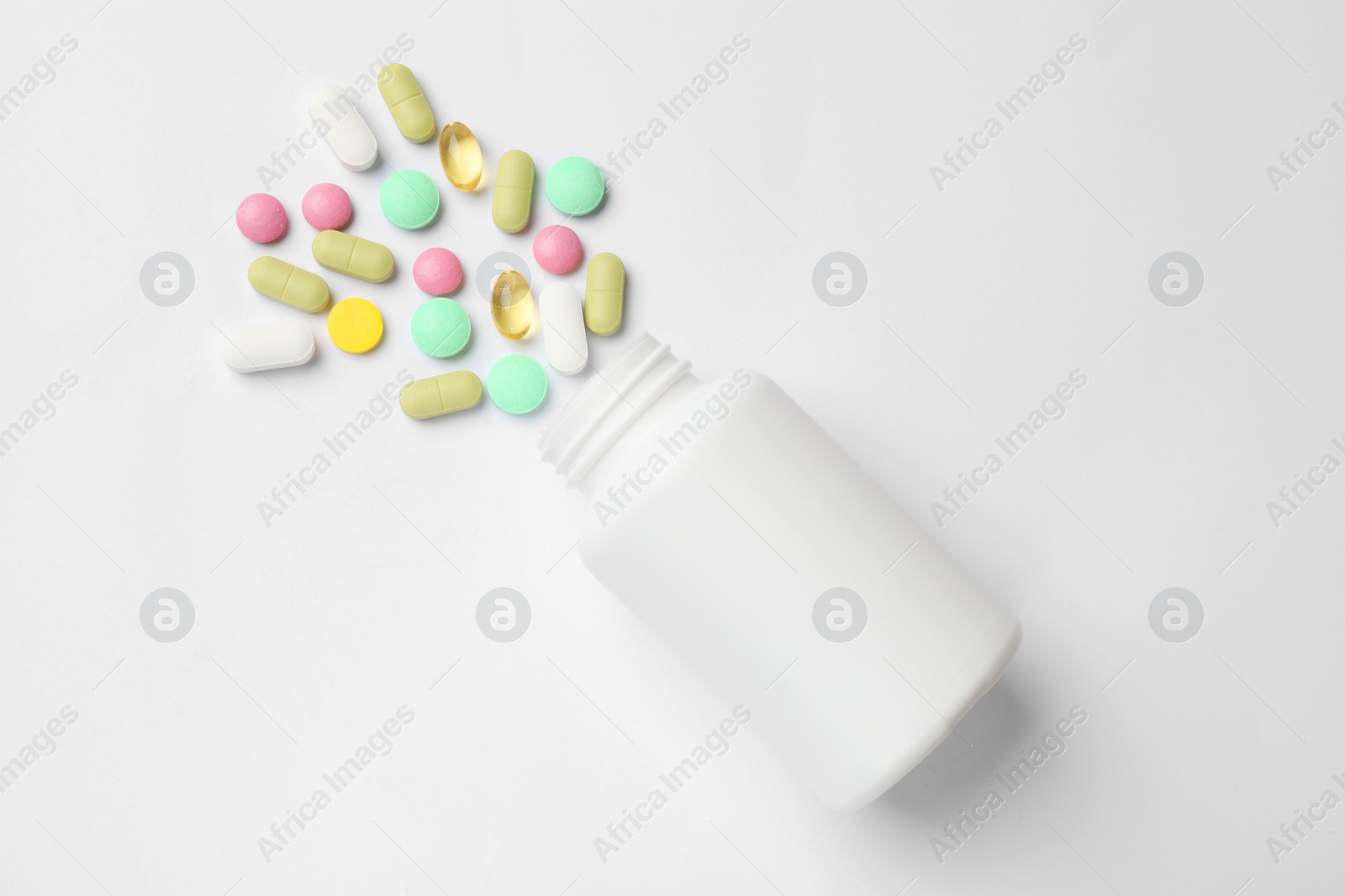 Photo of Different vitamin pills and bottle on white background, top view