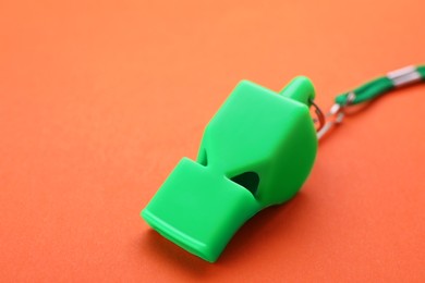 Photo of One green whistle with cord on orange background, closeup