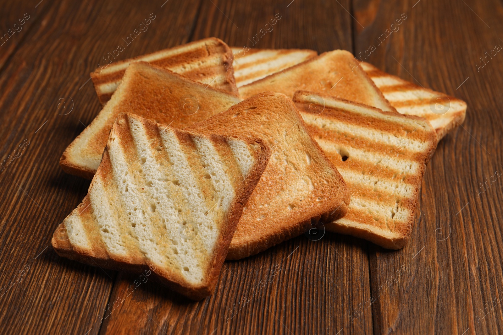 Photo of Slices of tasty toasted bread on wooden table