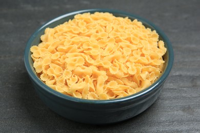 Photo of Raw farfalline pasta in bowl on grey table, closeup