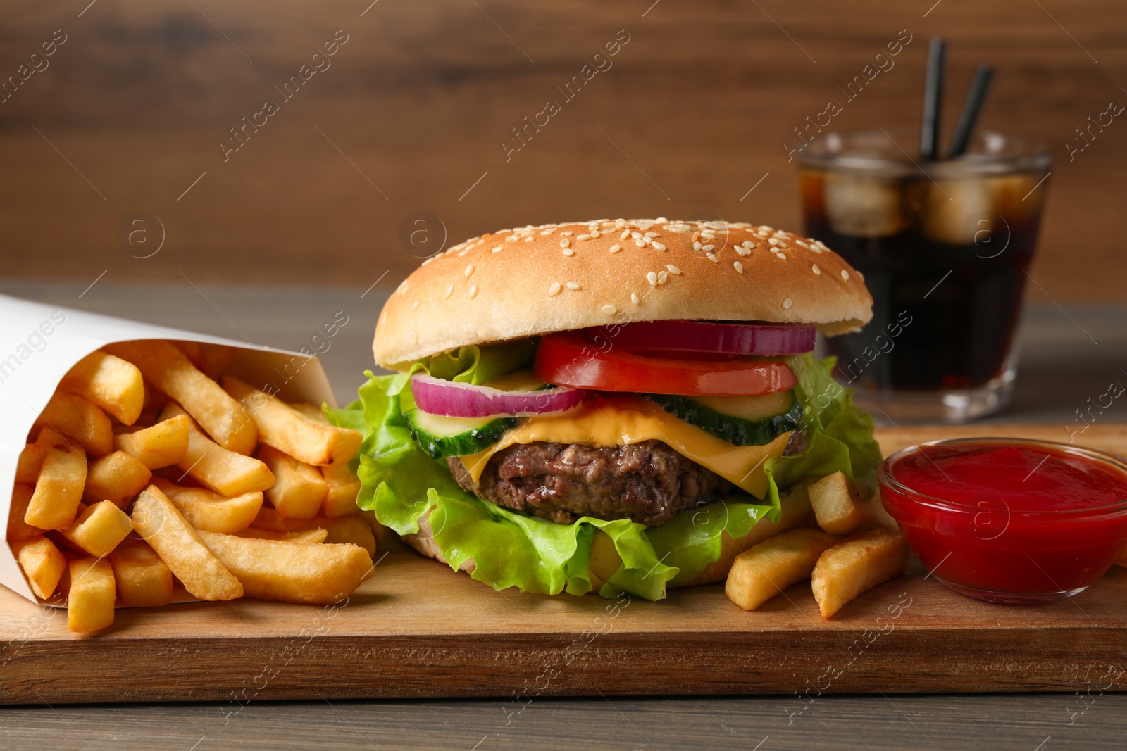 Photo of Delicious burger, soda drink and french fries served on wooden table, closeup