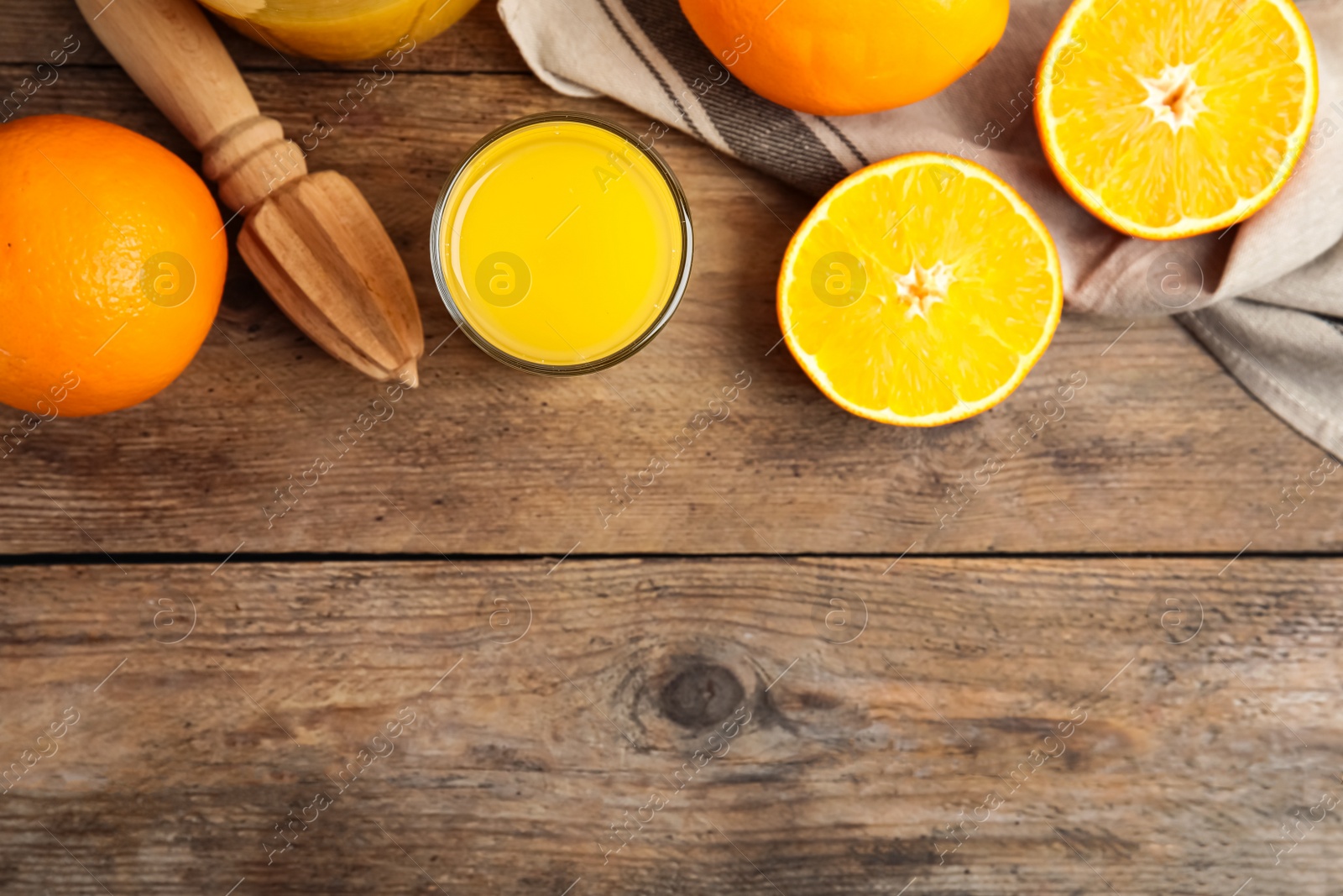 Photo of Fresh ripe oranges, reamer and juice on wooden table, flat lay. Space for text