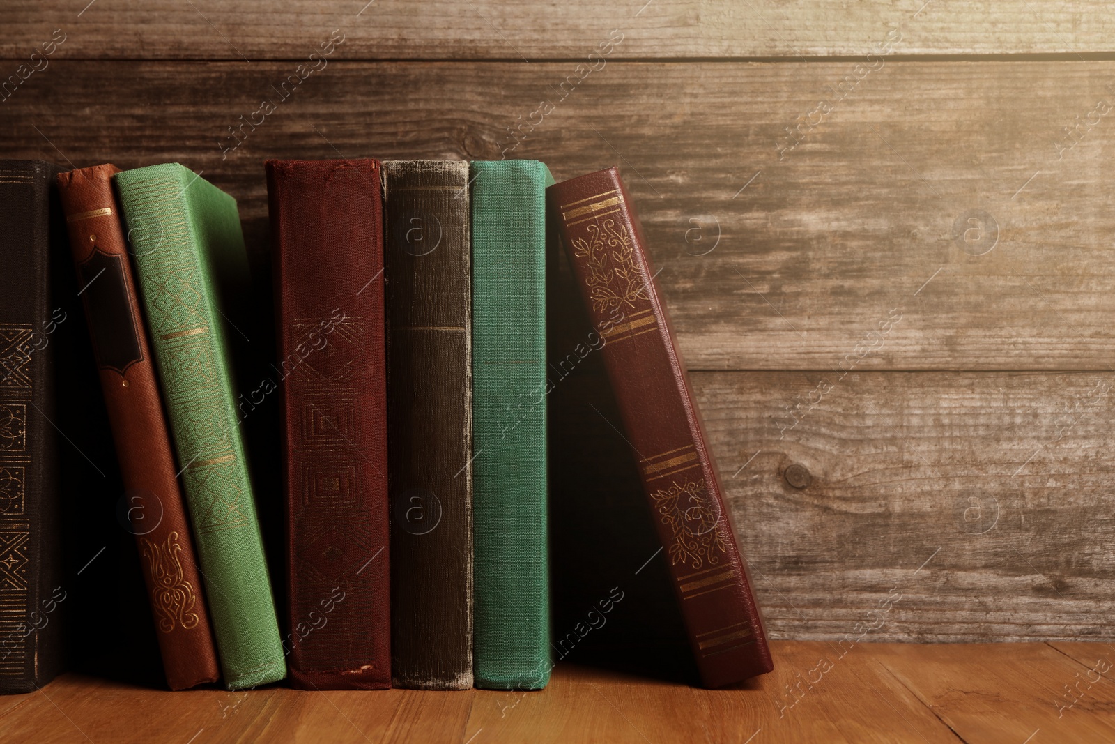 Image of Different old hardcover books on wooden table, space for text