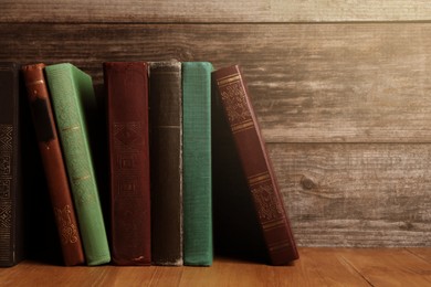 Different old hardcover books on wooden table, space for text