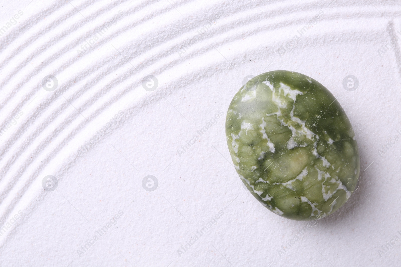 Photo of Stone on sand with pattern, top view. Zen concept