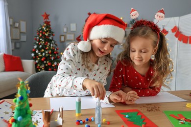 Cute little children making beautiful Christmas greeting cards at home