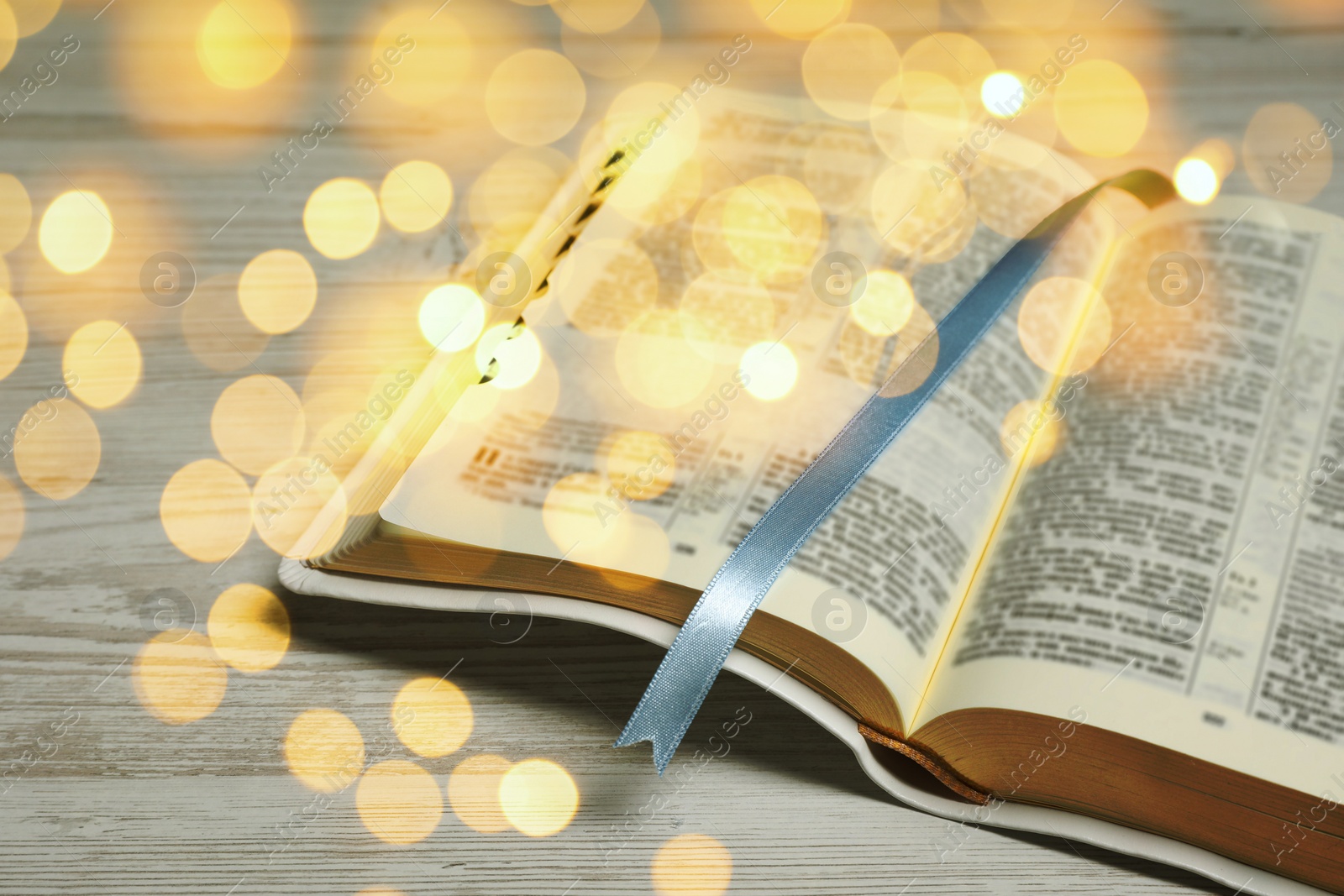 Image of Open Bible on wooden table, bokeh effect