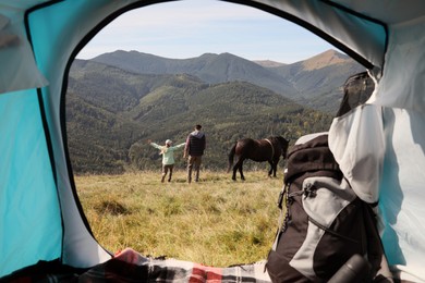 Photo of Couple and horse in mountains, view from camping tent