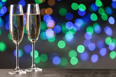 Photo of Glasses of champagne on table against blurred lights, space for text. Bokeh effect