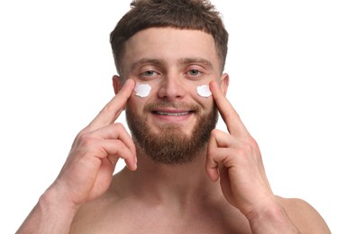 Photo of Handsome man applying moisturizing cream onto his face on white background