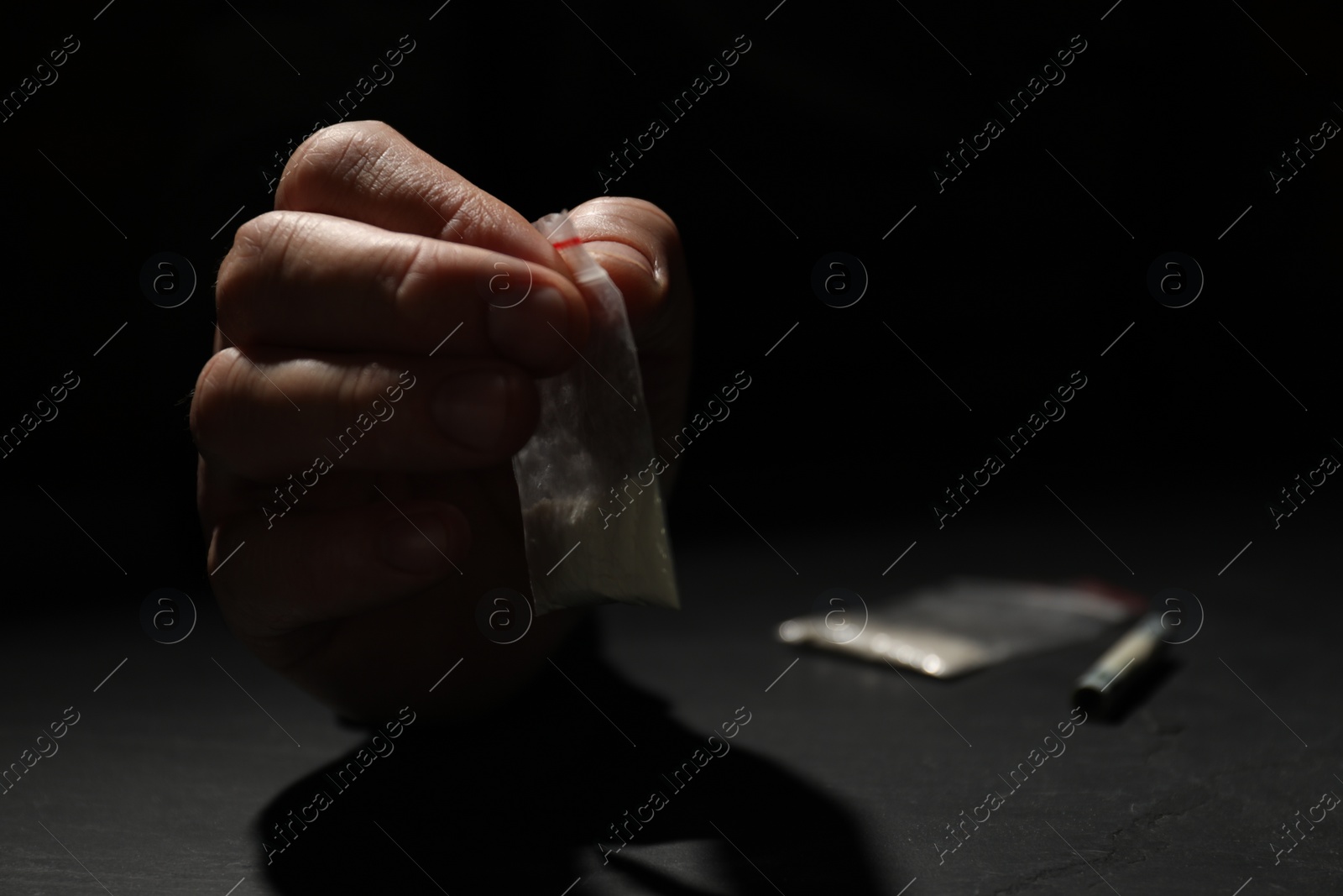 Photo of Drug addiction. Man with plastic bag of cocaine at grey table, selective focus