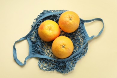 String bag with oranges on beige background, top view