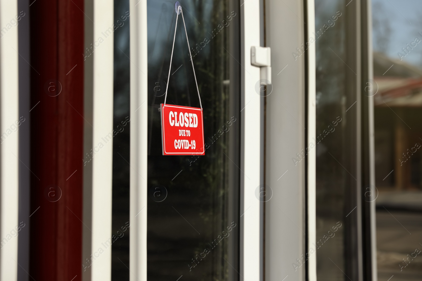 Photo of Red sign with text Closed Due To Covid-19 hanging on glass door. Coronavirus quarantine