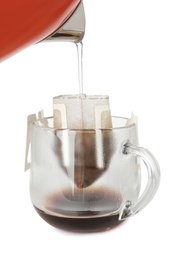 Photo of Pouring hot water into glass cup with drip coffee bag on white background