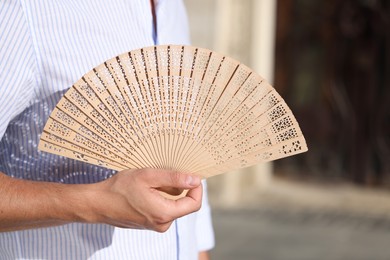 Photo of Man with hand fan outdoors, closeup view