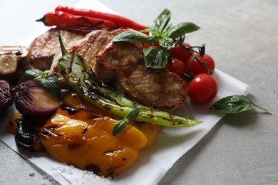 Tasty grilled meat and vegetables on light table, closeup