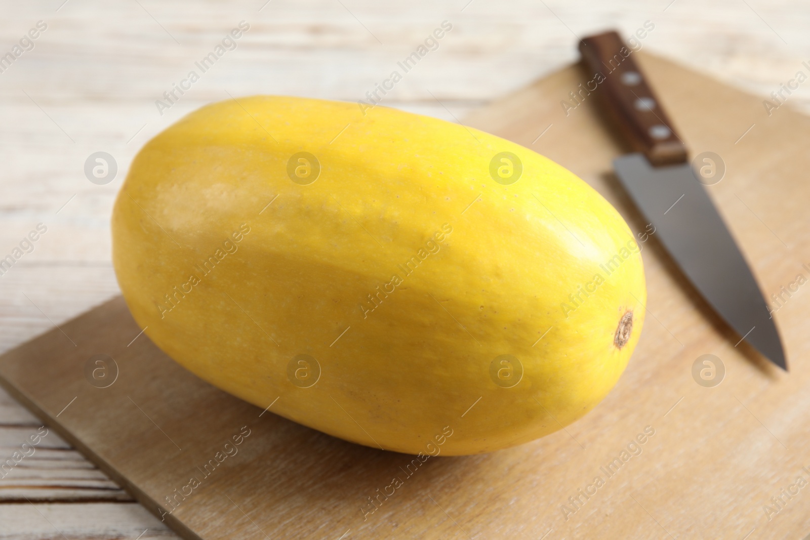 Photo of Ripe spaghetti squash and knife on wooden board