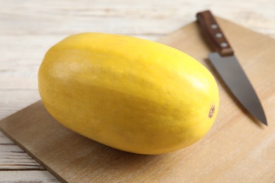 Photo of Ripe spaghetti squash and knife on wooden board