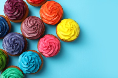 Photo of Many delicious colorful cupcakes on light blue background, flat lay. Space for text