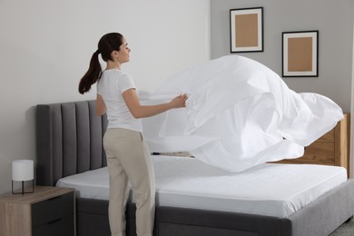 Young woman changing bed linens at home