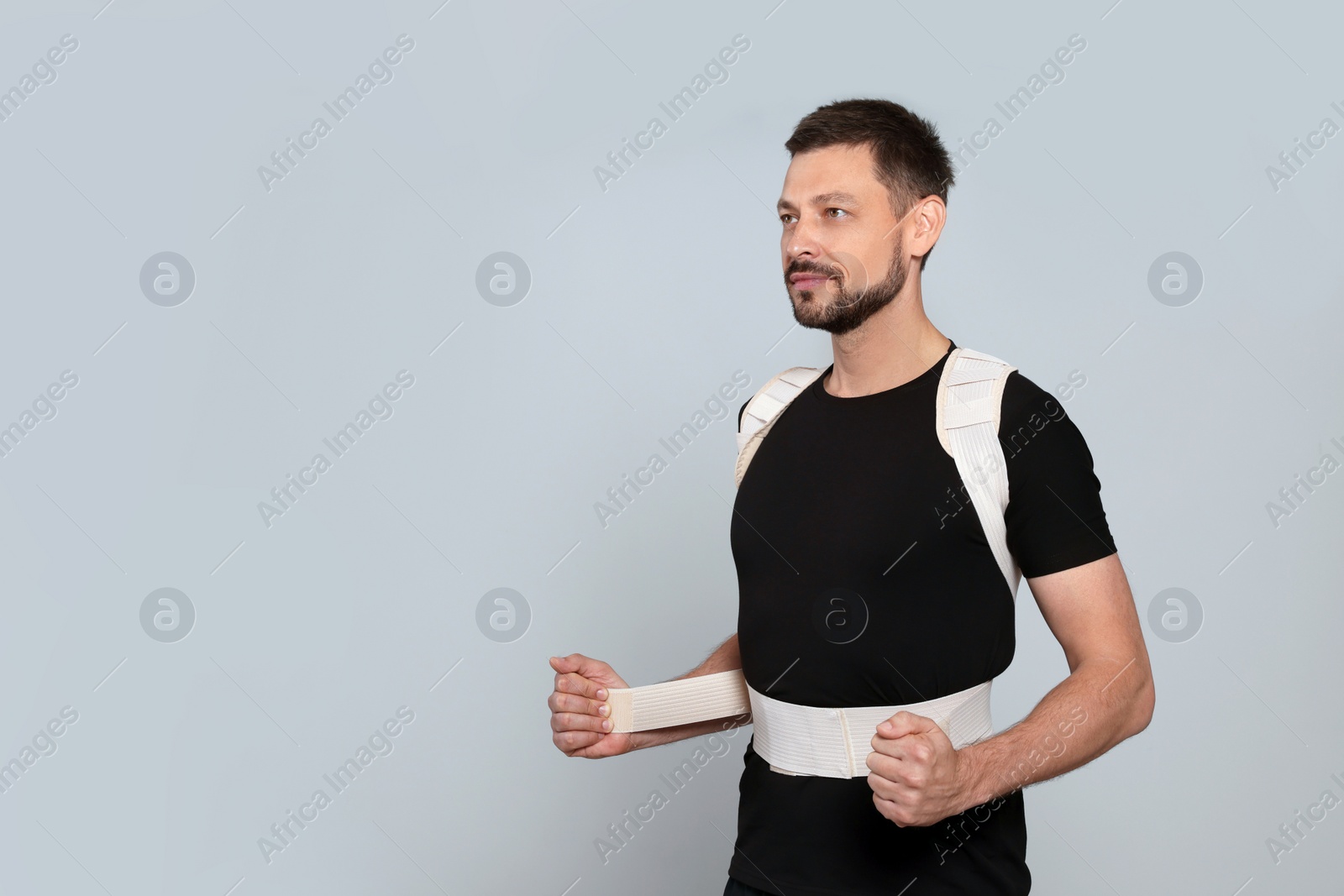 Photo of Handsome man with orthopedic corset on grey background, space for text