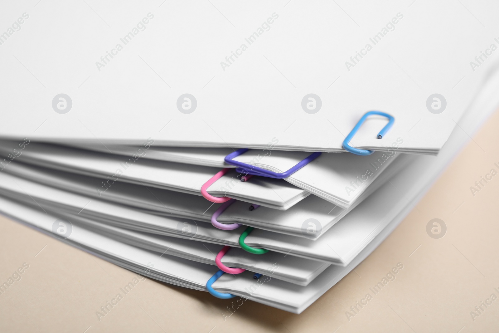 Photo of Sheets of paper with clips on beige background, closeup