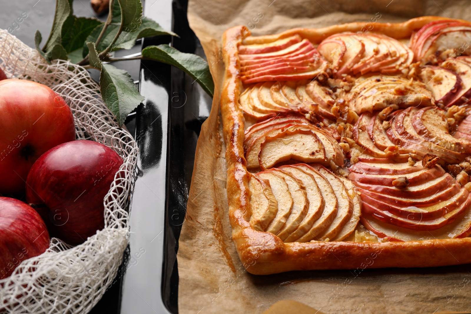 Photo of Baking tray with fresh apple galette and fruits on black table, closeup