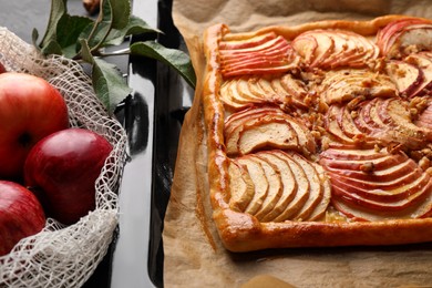 Photo of Baking tray with fresh apple galette and fruits on black table, closeup