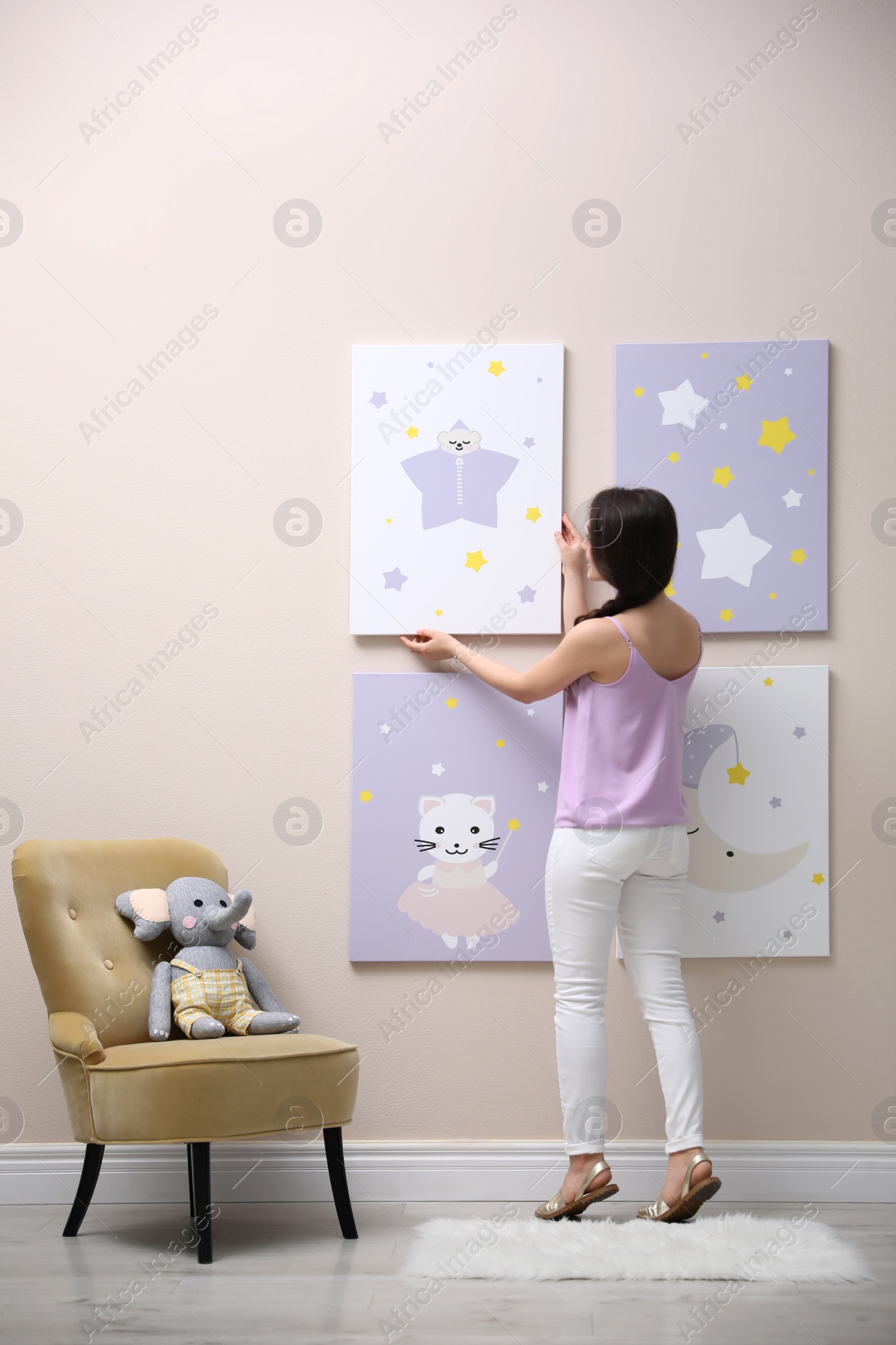 Photo of Decorator hanging picture on pink wall. Children's room interior design