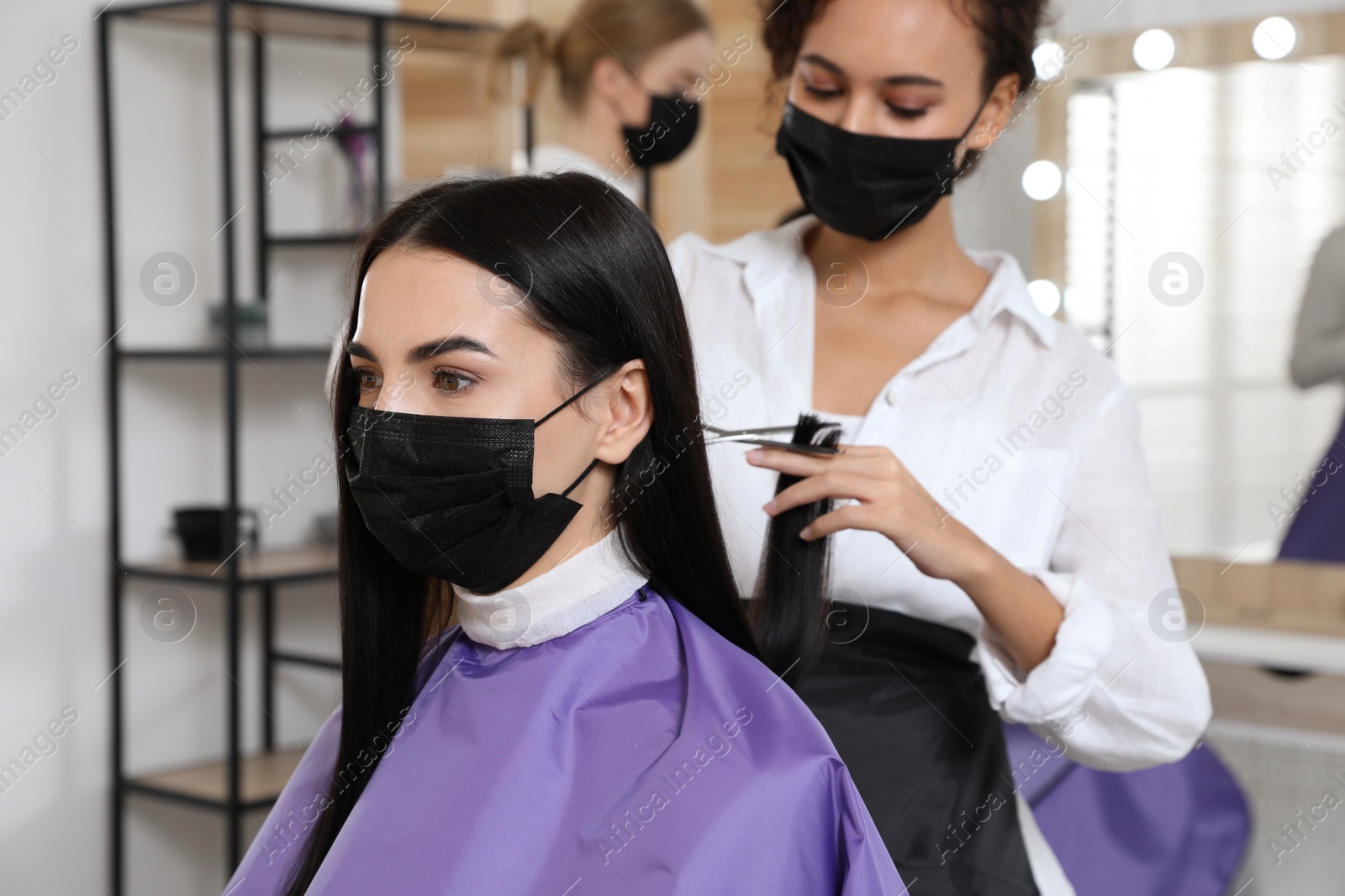 Photo of Professional stylist working with client in salon. Hairdressing services during Coronavirus quarantine