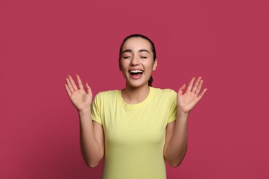 Beautiful young woman laughing on maroon background. Funny joke