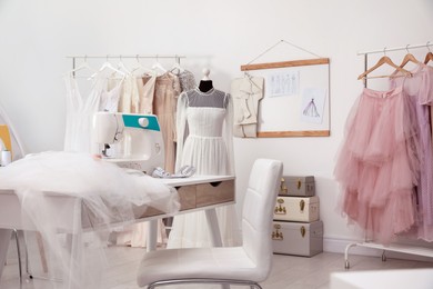Photo of Dressmaking workshop interior with wedding dresses, female clothes and equipment