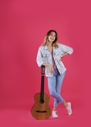 Young woman with acoustic guitar on color background