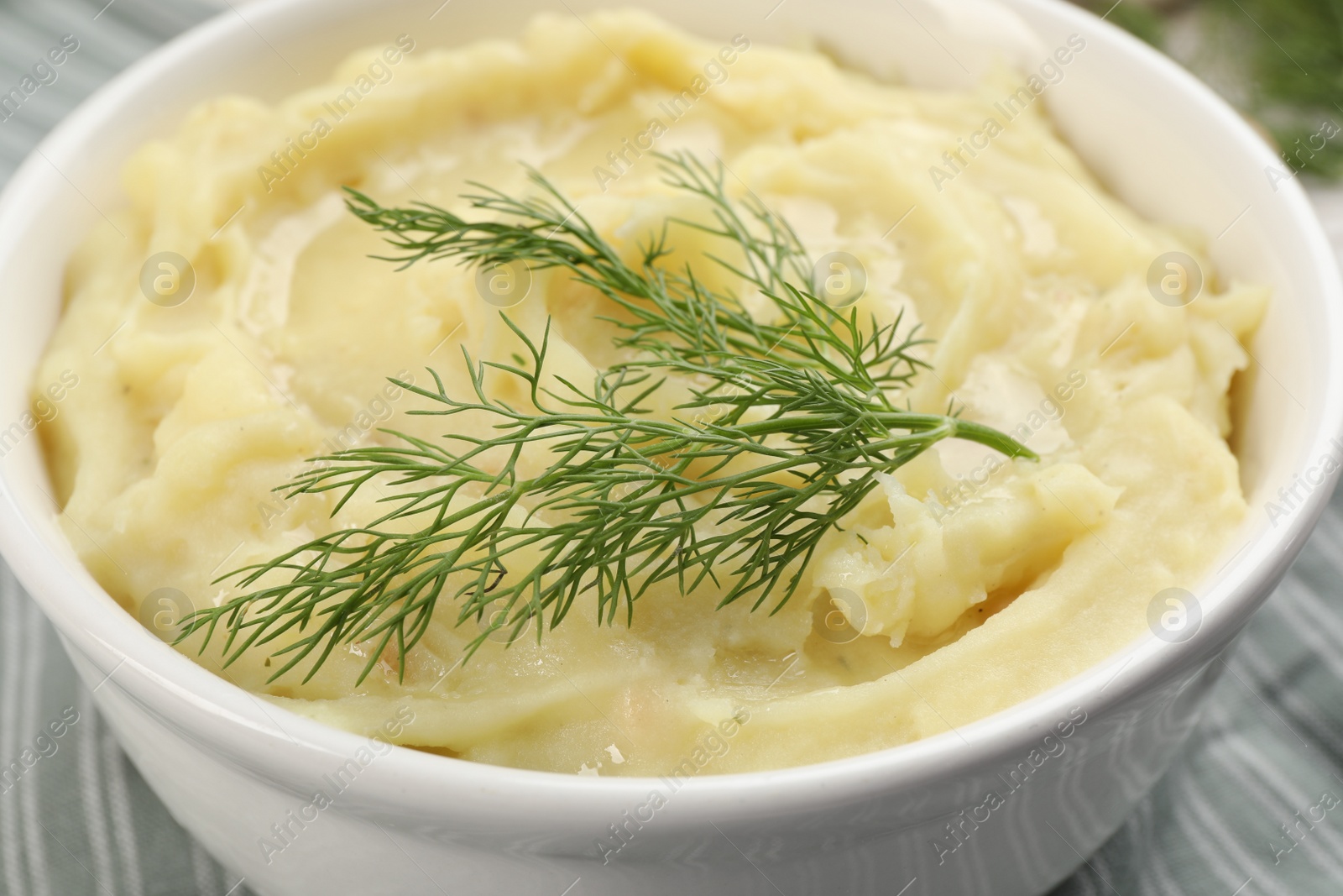 Photo of Bowl of tasty mashed potato with dill on table, closeup