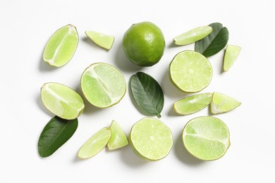 Photo of Fresh ripe limes and leaves on white background, flat lay