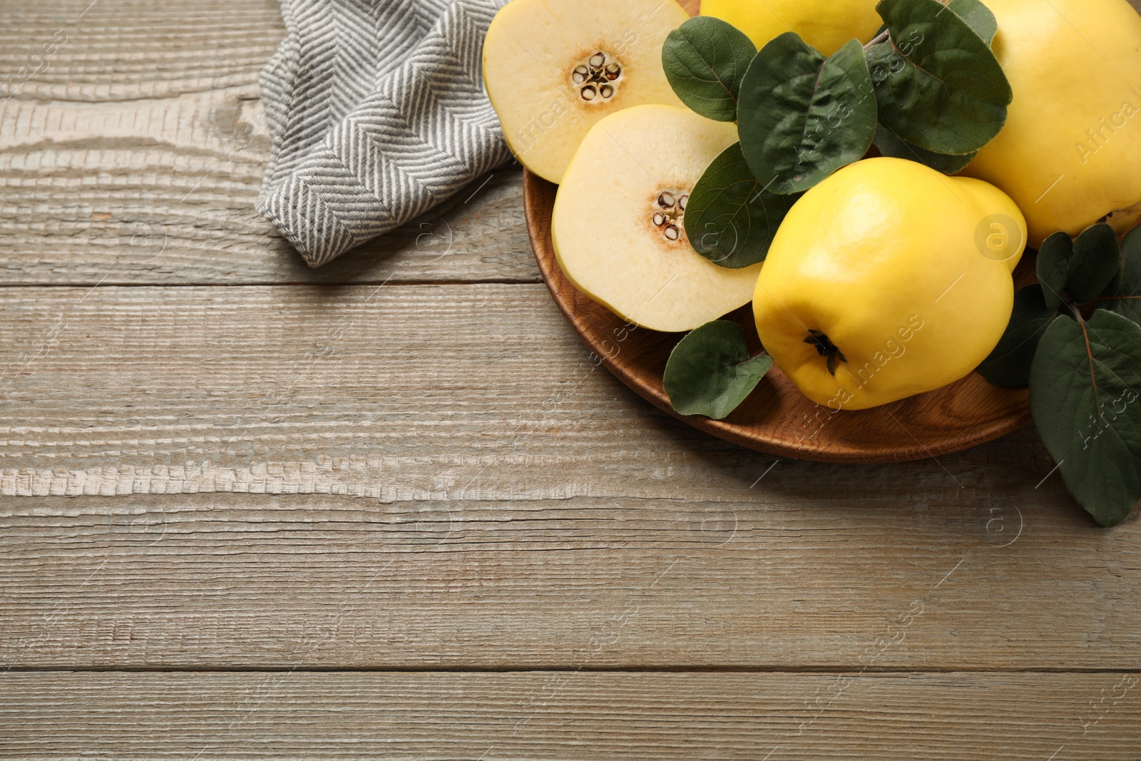 Photo of Fresh ripe organic quinces with leaves on wooden table, above view. Space for text