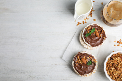 Puffed rice cakes with chocolate spread on white wooden table, flat lay. Space for text