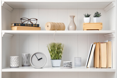 Photo of White shelving unit with plants and different decorative stuff