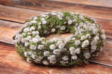 Photo of Wreath made of beautiful willow flowers on wooden table, closeup