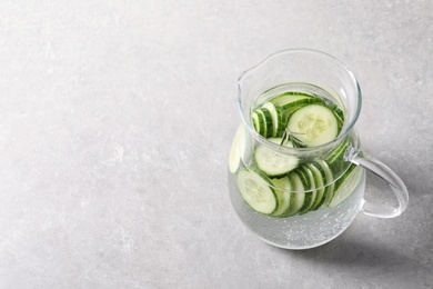 Jug of fresh cucumber water on grey background. Space for text