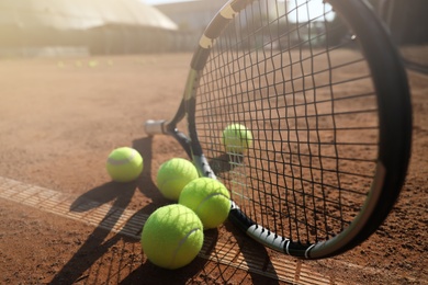 Tennis balls and racket on clay court, closeup